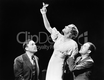 Two men supporting a woman lifting her wine glass