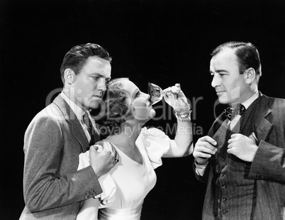 Two men supporting a woman drinking