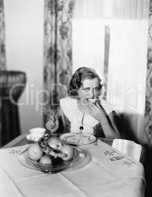 Portrait of a woman sitting at a table and eating a piece of bread
