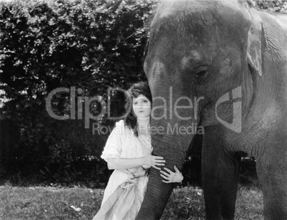 Young woman hugging the trunk of an elephant