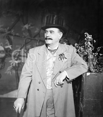 Portrait of man leaning against a potted plant