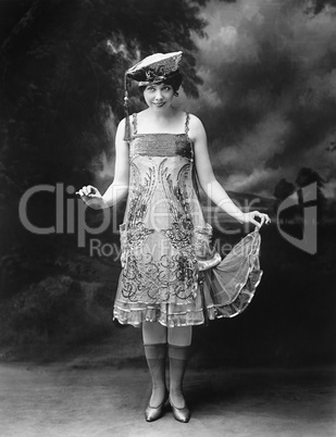 Woman wearing a hat and ornate dress and smiling