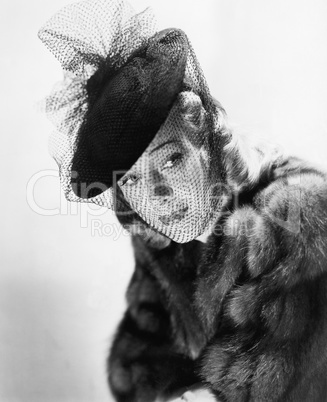 Portrait of a young woman wearing a fur and a hat with a veil