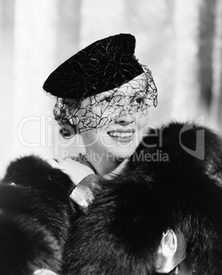 Portrait of a young woman in a hat with a veil and a fur stole smiling