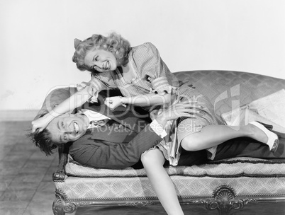 Couple having a playful fight on a couch