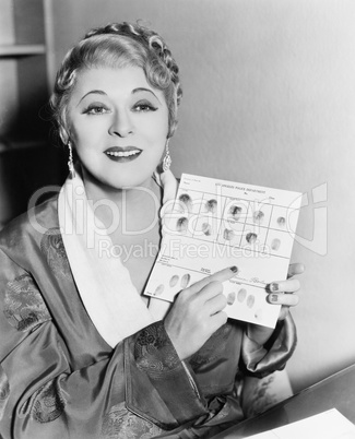 Young woman showing fingerprint on a sheet of paper