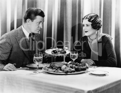 Man offering food to a woman in a restaurant