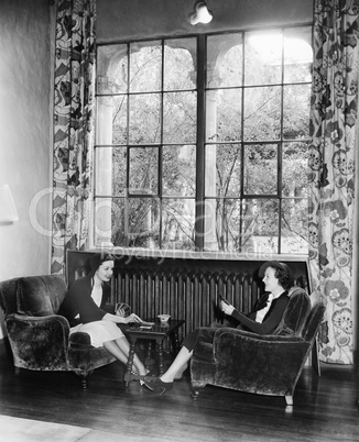 Two women playing cards and sitting together