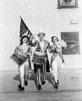 Marching band performing in a parade with an American flag