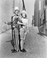 Profile of a young man and a young woman standing with arm in arm in a costume
