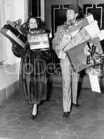 Couple walking and holding stacks of presents
