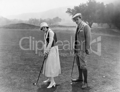 Profile of a couple playing golf in a golf course