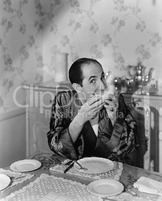 Portrait of a mature man sitting at the dining table and eating fruit