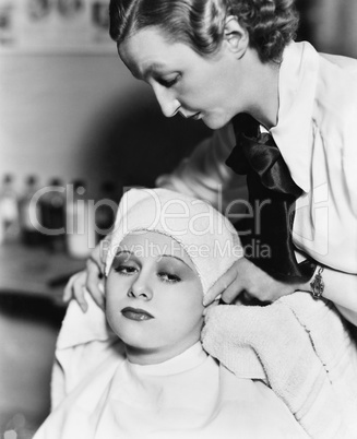 Female hairdresser drying hair of a young woman with a towel in a hair salon