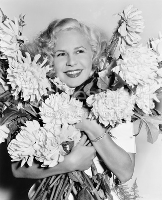 Portrait of a young woman holding a bunch of flowers looking happy