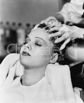 Hairdresser cleaning hair of a young woman in a hair salon