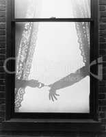 Silhouette of a hand arresting a person with handcuffs viewed through a window