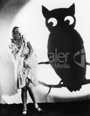 Young woman looking at a shadow of an owl with her finger on her lips