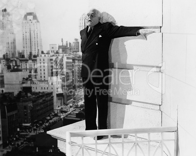 Man standing on the ledge of a building and looking feared