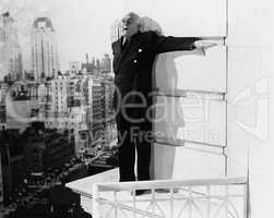 Man standing on the ledge of a building and looking feared