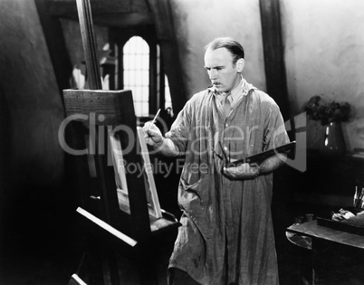 Man painting on an easel with a paintbrush