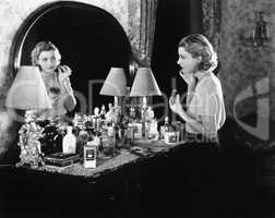 Young woman in front of her vanity applying make-up