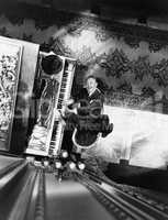 High angle view of a man reclining on a chair and playing a piano