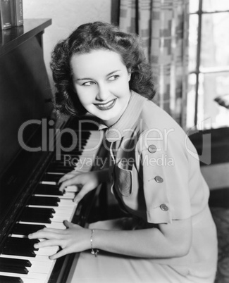 Profile of a young woman playing a piano and smiling