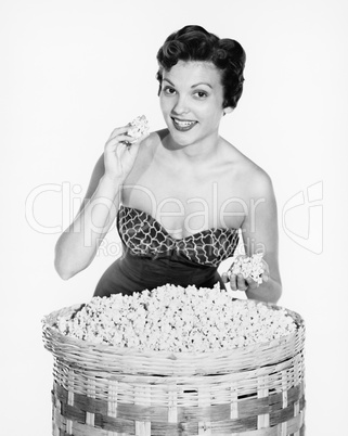 Portrait of a young woman showing popcorn and smiling