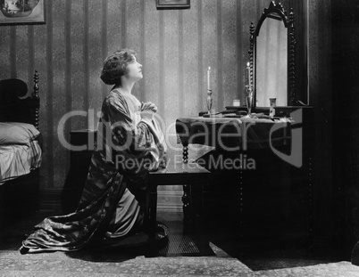 Profile of a young woman pleading in front of a mirror in her bed room