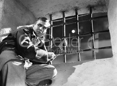 Low angle view of a young man trying to escape from a prison cell