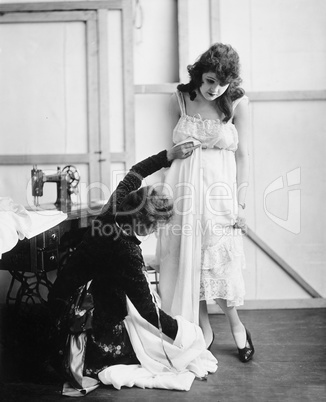 Profile of a female tailor taking measurement of a young woman in a bridal shop