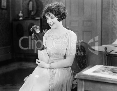 Young woman looking at a monkey hand puppet and smiling