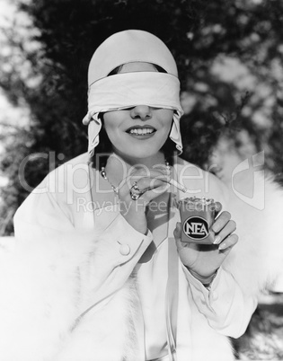 Young woman with blindfolded eyes taking out a cigarette from a cigarette pack