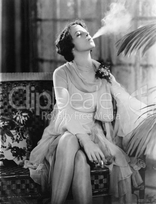 Young woman sitting on a couch smoking a cigarette