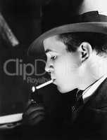 Close-up of a young man with a hat lighting a cigarette with a cigarette lighter