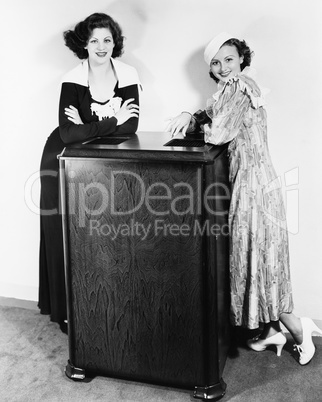 Portrait of two young women leaning against an air conditioner