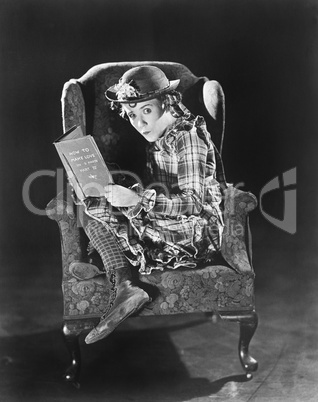 Profile of a girl sitting in an armchair holding a book