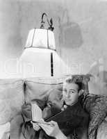 Man lying on a couch and holding a book
