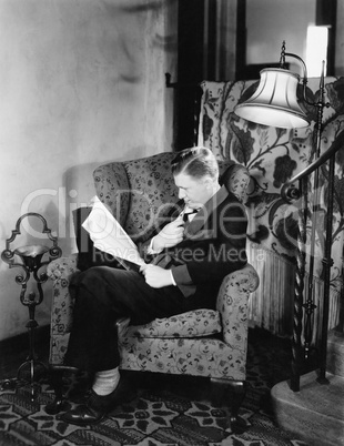 Profile of a man sitting in an armchair and reading a book