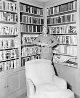 Man leaning against a bookshelf in a library