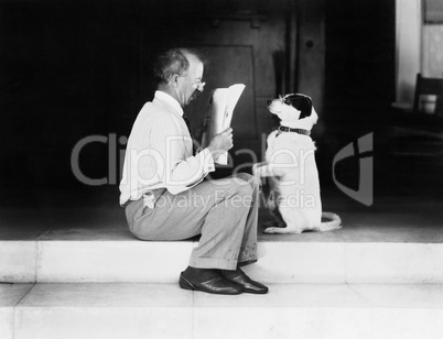 Man reading a newspaper with his dog