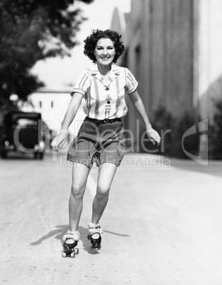 Portrait of a young woman skating on the road and smiling