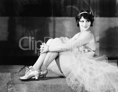 Profile of a young woman hugging her knees and smiling