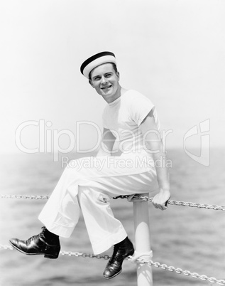 Portrait of a sailor sitting on the pole of a boat and smiling