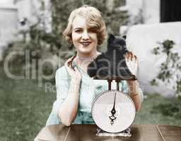 Portrait of a young woman weighing her puppy on a weighing scale