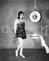 Portrait of a young woman weighing her clothes on a weighing scale