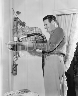 Profile of a man cleaning a cage with a vacuum cleaner