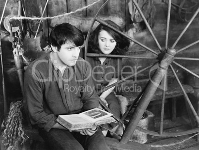 Young man reading a book and a young woman sitting beside him