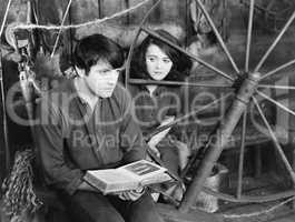 Young man reading a book and a young woman sitting beside him